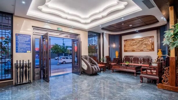 A lobby with a marble floor, a massage chair, traditional wooden furniture, and a large wall painting. - Vyluk Hotel Jianshui Gucheng (Honghe)