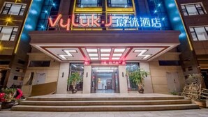 A hotel entrance with a modern facade, illuminated signage, and a set of steps leading to the entrance. - Vyluk Hotel Jianshui Gucheng (Honghe)