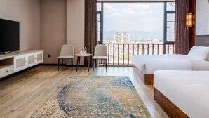A hotel room with a large window, a TV, two beds, a desk, and a chair. - Vyluk Hotel Jianshui Gucheng (Honghe)