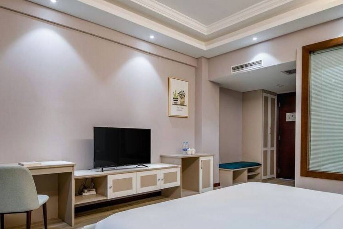 Una habitación de hotel con una cama, un escritorio con televisor, una silla y una mesita.