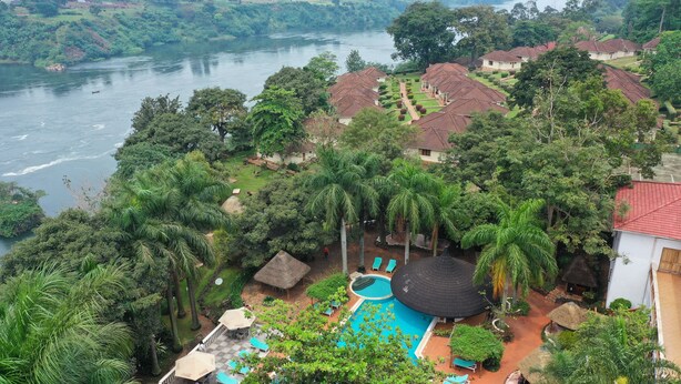 Un resort con piscina, sillones de descanso y vistas al río.
