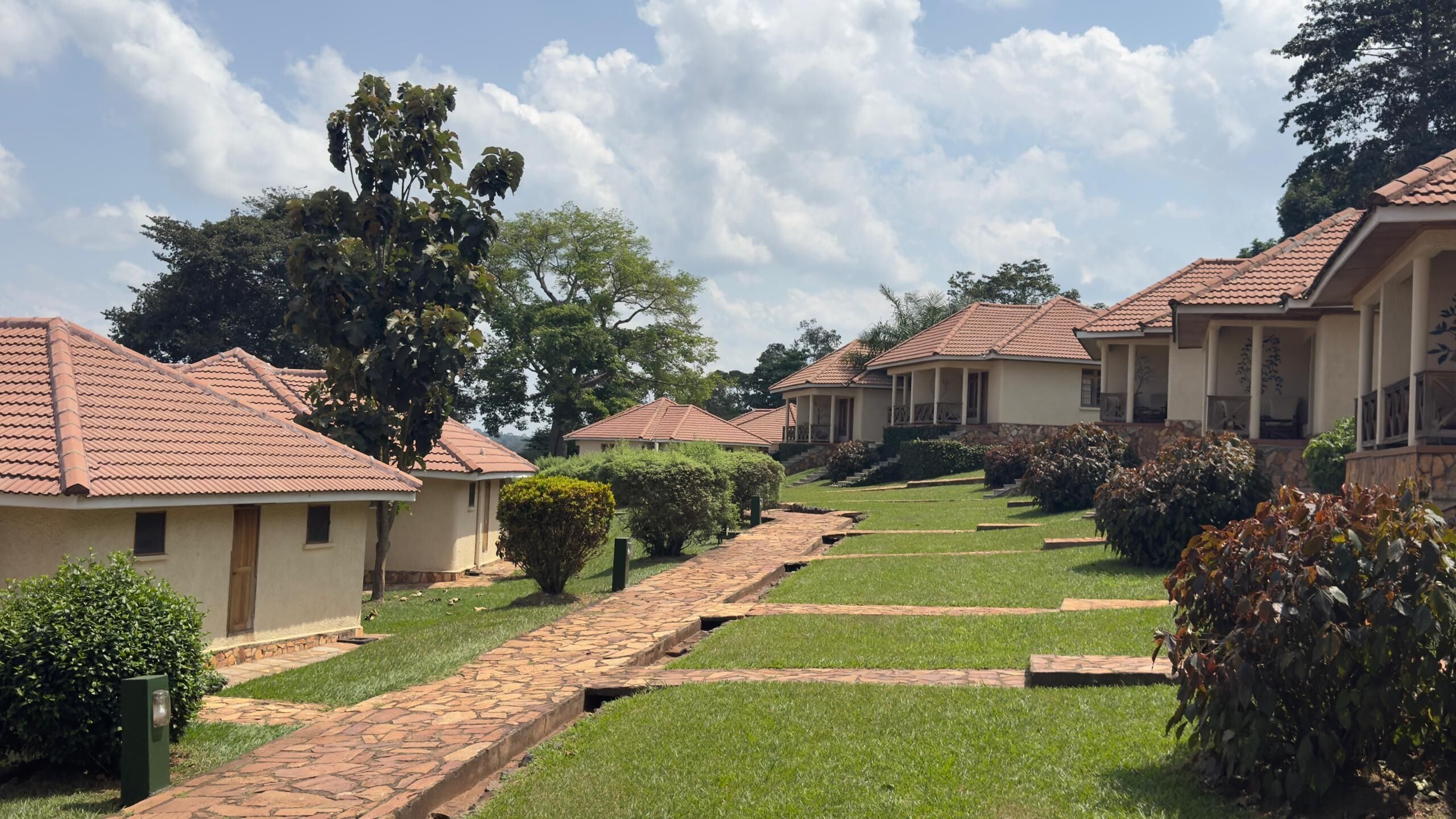 A row of single-story buildings with tiled roofs, a paved pathway, and well-maintained lawns.