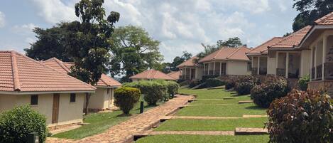 A row of single-story buildings with tiled roofs, a paved pathway, and well-maintained lawns.