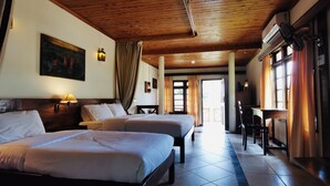 Habitación de hotel con dos camas, techo de madera, un cuadro en la pared y vista al pasillo.