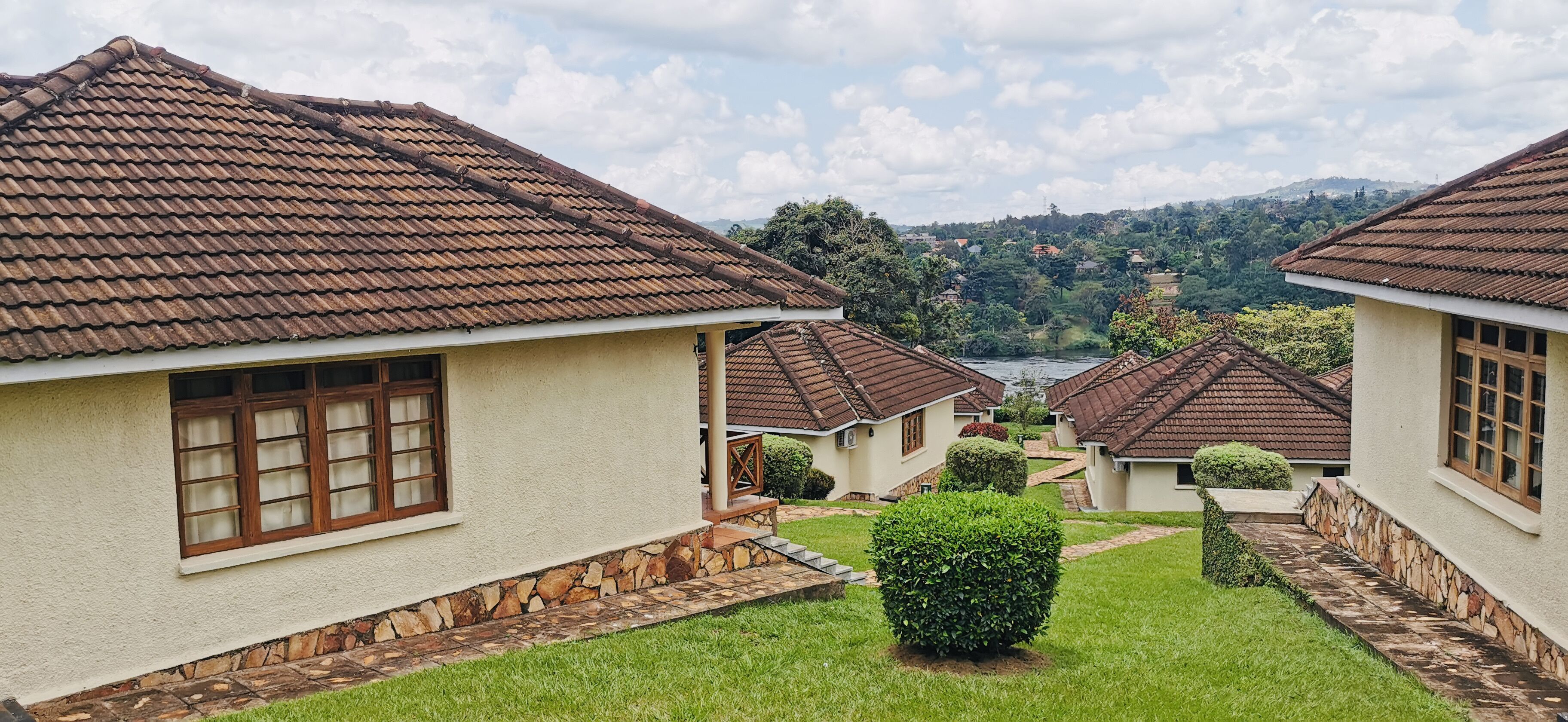 A row of houses with brown tiled roofs, stone steps, and a grassy lawn.