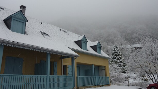 A two-story house with a snow-covered roof and a porch.