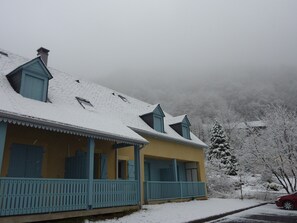 Een twee verdiepingen tellend huis met een sneeuwbedekte dak en een veranda.