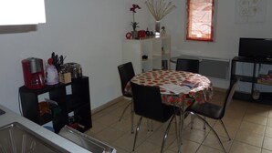 A compact kitchen with a dining area, a coffee maker, and a TV.