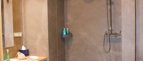 A modern bathroom with a shower, a sink, and a towel rack.