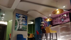 A modern bar area with colorful chairs, a large abstract painting, and a pink neon-lit shelf. - 73 Boutique Hotel   (Como)