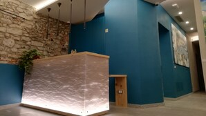 A reception area with a marble counter, stone wall, blue walls, and modern lighting. - 73 Boutique Hotel   (Como)