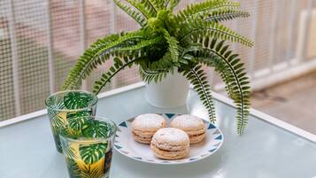 A table with a glass of iced tea, a plate of macarons, and a potted fern.