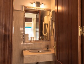 Een badkamer met een wastafel, spiegel en douche.