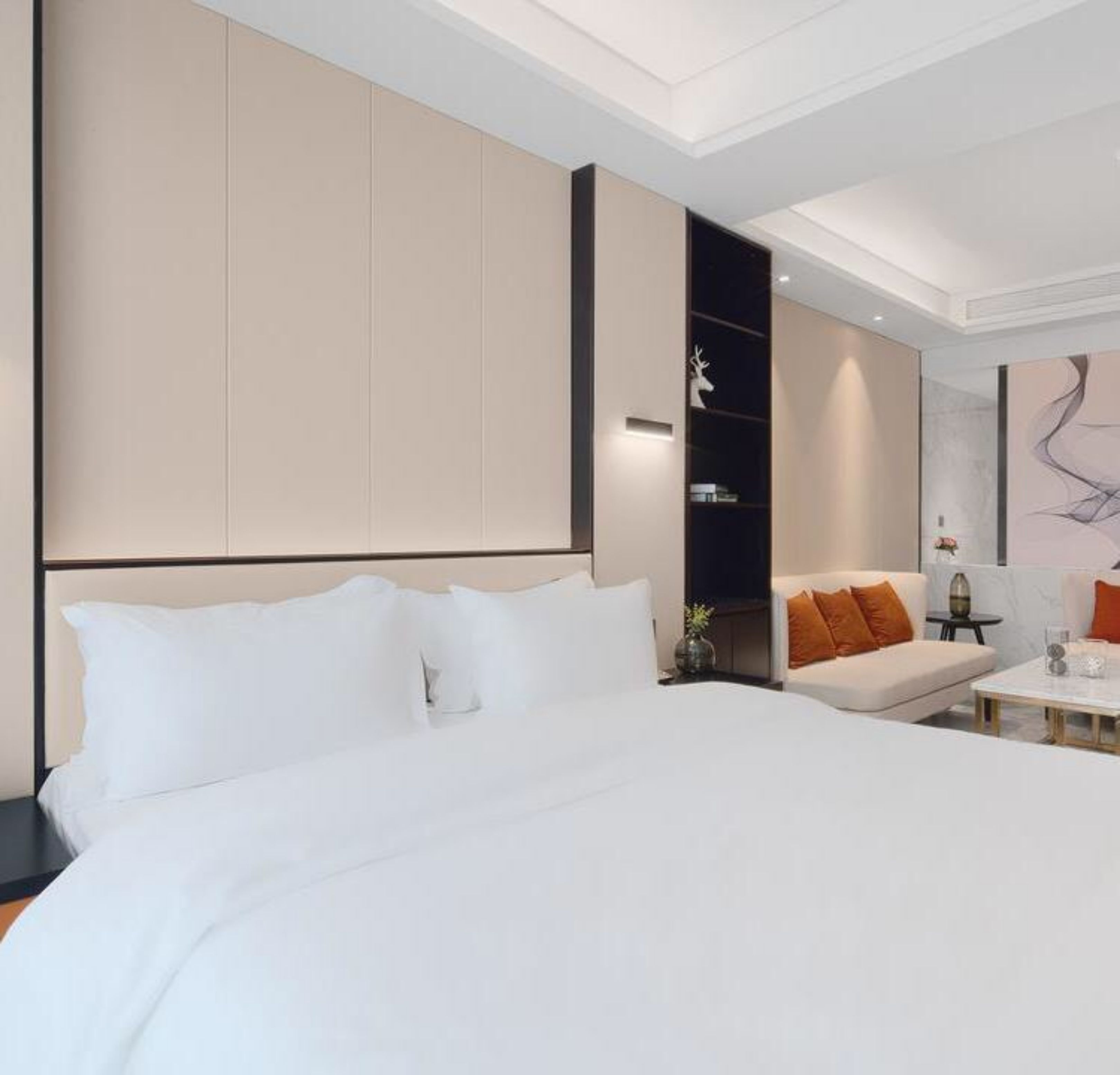 A modern hotel room with a large bed, a sofa, and a small table.