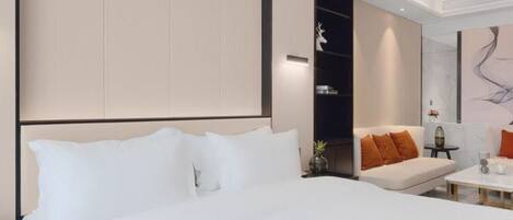 A modern hotel room with a large bed, a sofa, and a small table.