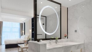 A modern bathroom with a large mirror, marble countertop, and a bed in the adjacent room. - Vyluk Hotel Chengdu UESTC (Chengdu)