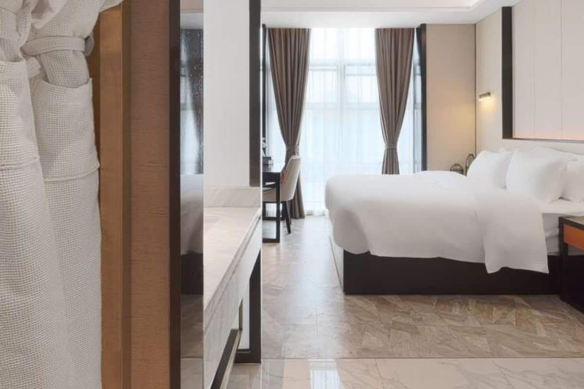 Ein Hotelzimmer mit einem großen Bett, einem Schreibtisch und einem Stuhl. Ein Bademantel hängt an der Tür.