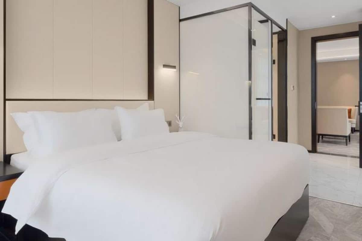 Ein modernes Hotelzimmer mit einem großen Bett, einem Nachttisch, einem Schreibtisch und einem Sessel.