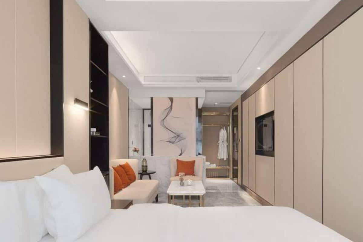 Ein modernes Hotelzimmer mit einem großen Bett, einer Couch, einem kleinen Tisch und einem begehbaren Kleiderschrank.