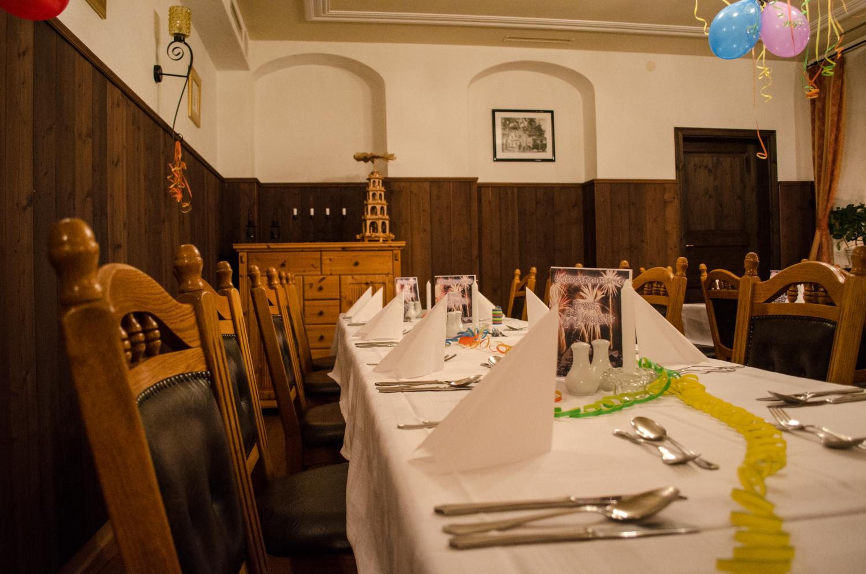 A dining room with wooden chairs and tables, a small decorative tower, and a framed picture on the wall.