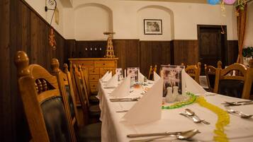 A dining room with wooden chairs and tables, a small decorative tower, and a framed picture on the wall.