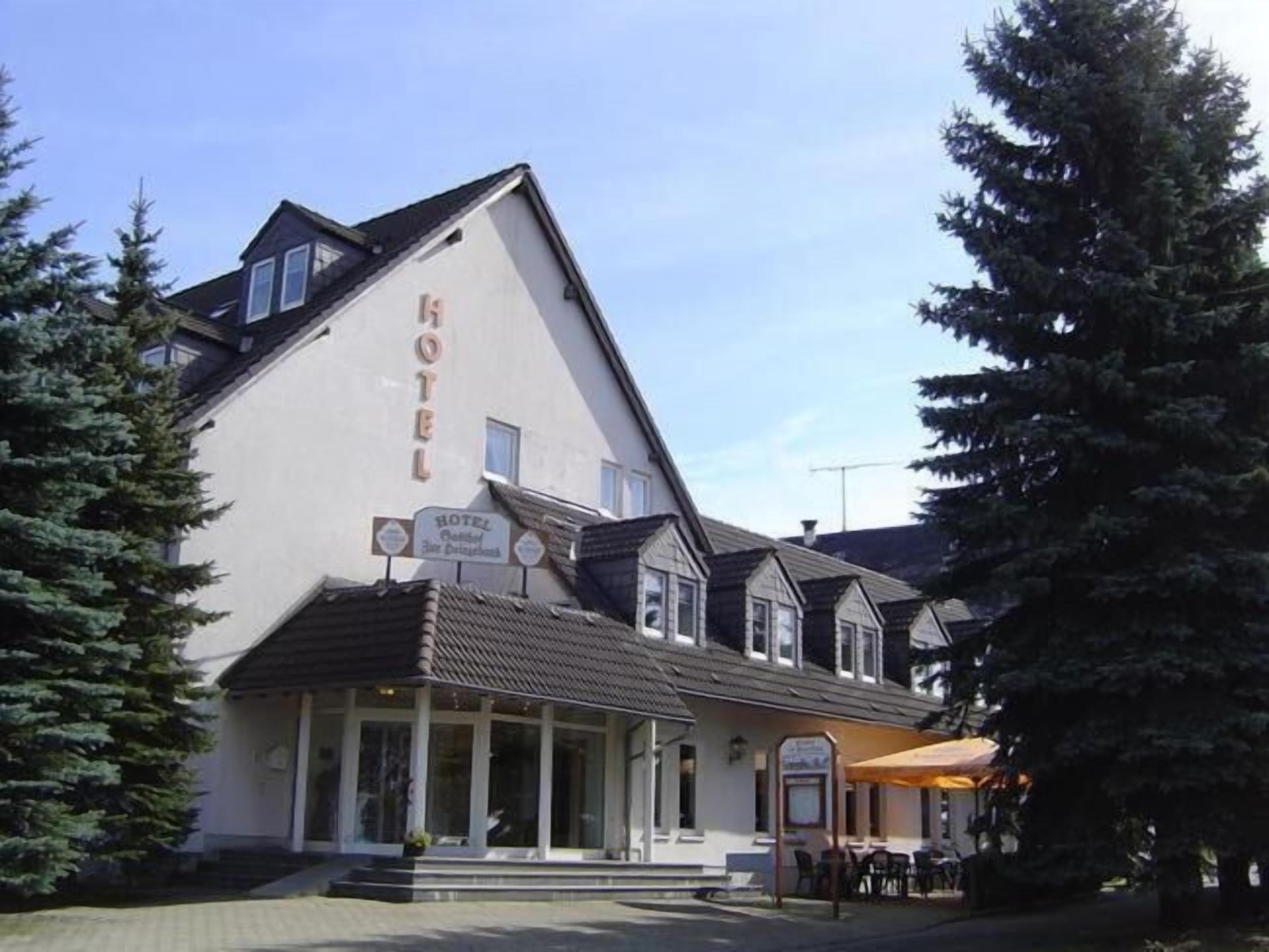 Un hotel con un llamativo letrero que dice 'HOTEL' en la fachada, un área de estar al aire libre techada y un estilo arquitectónico tradicional con un techo pronunciado.