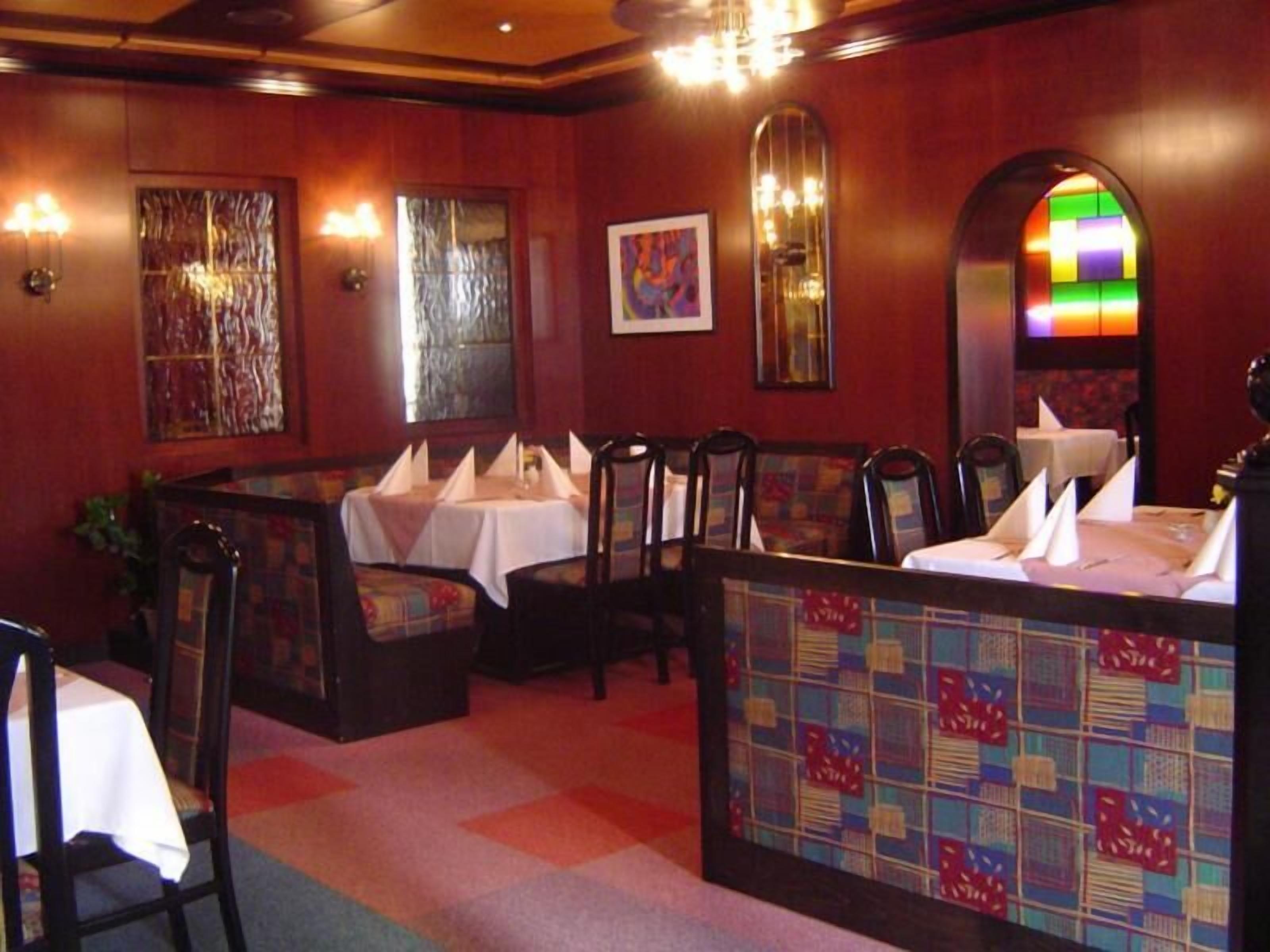 A restaurant with booths and tables, wooden paneling, and a stained glass window.