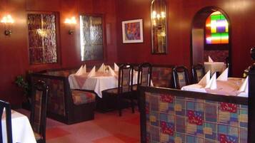 A restaurant with booths and tables, wooden paneling, and a stained glass window.