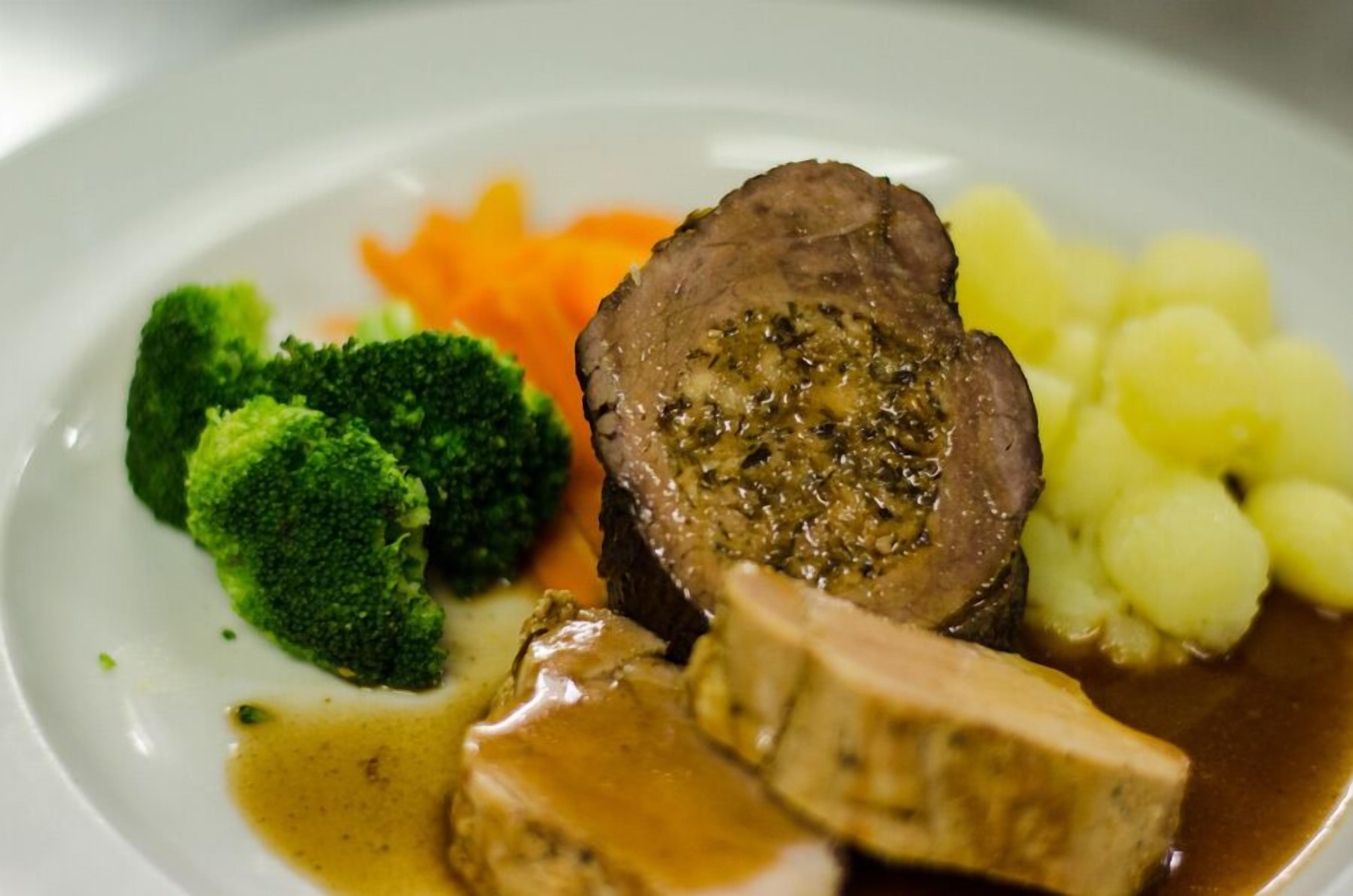 A plate with sliced beef, broccoli, carrots, and potatoes.