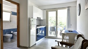 A modern kitchen with white cabinets, a built-in oven, and a dining area with a table and chairs. - Casa Cala Sisine (Baunei)