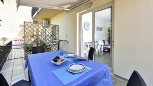 A dining area with a table set for two, a bowl of fruit, and a pizza box. - Casa Cala Sisine (Baunei)