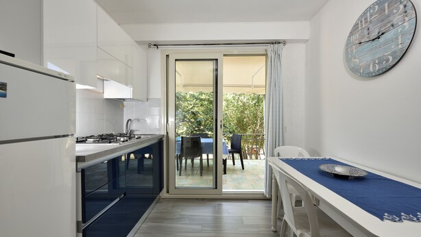 A compact kitchen with a sliding glass door leading to an outdoor dining area. - Casa Cala Sisine (Baunei)