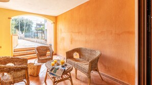 Una habitación con muebles de mimbre, una mesa con un periódico y un vaso de zumo de naranja.