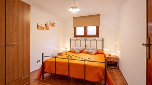 Un dormitorio con cama, armario de madera y ventana con persianas.