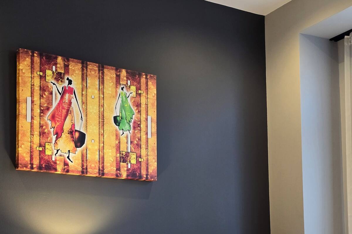A hotel room with two beds, a nightstand with a lamp, and a painting on the wall.