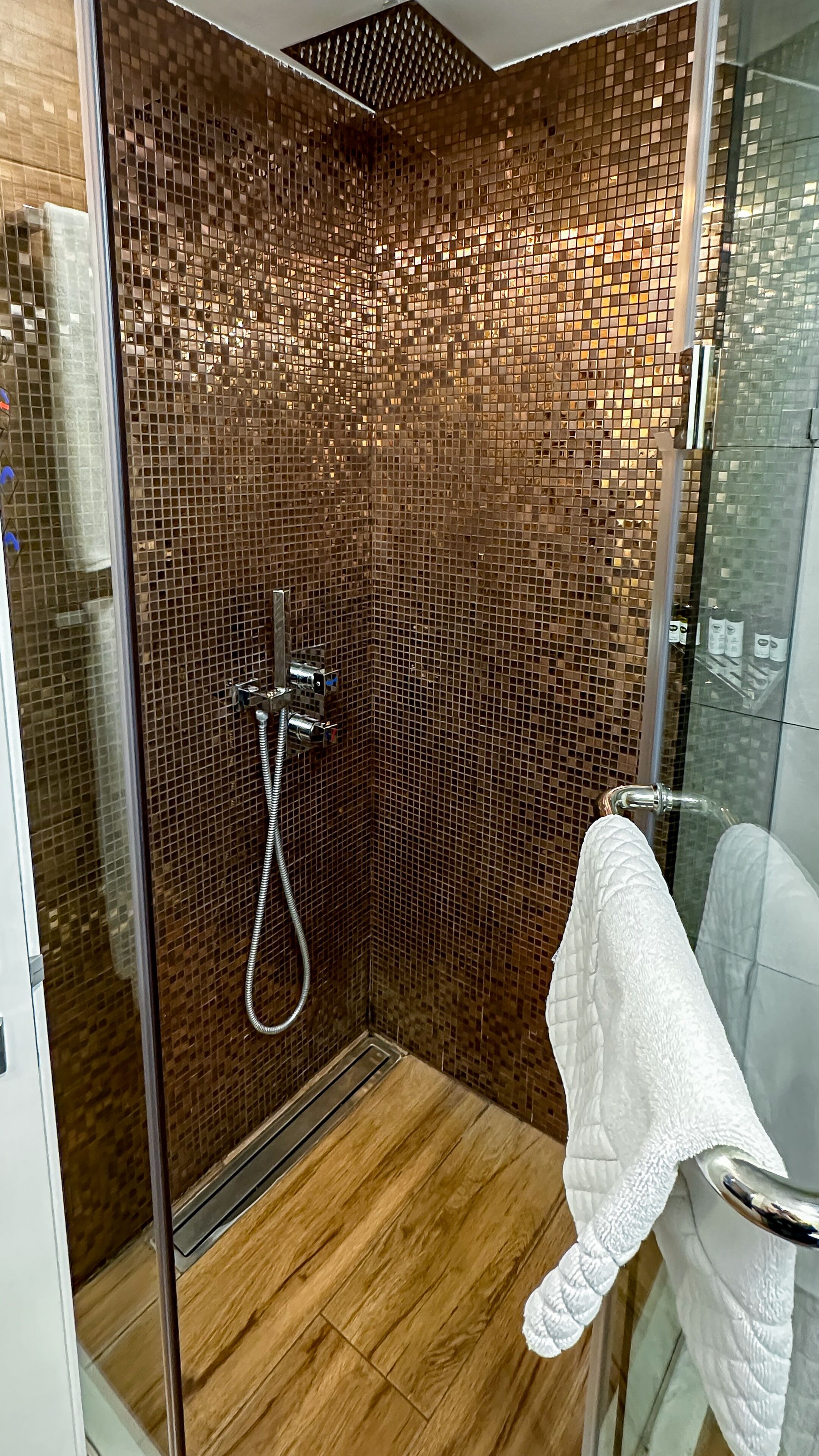 Un baño moderno con cabina de ducha de vidrio, una toalla blanca y pared con azulejos.