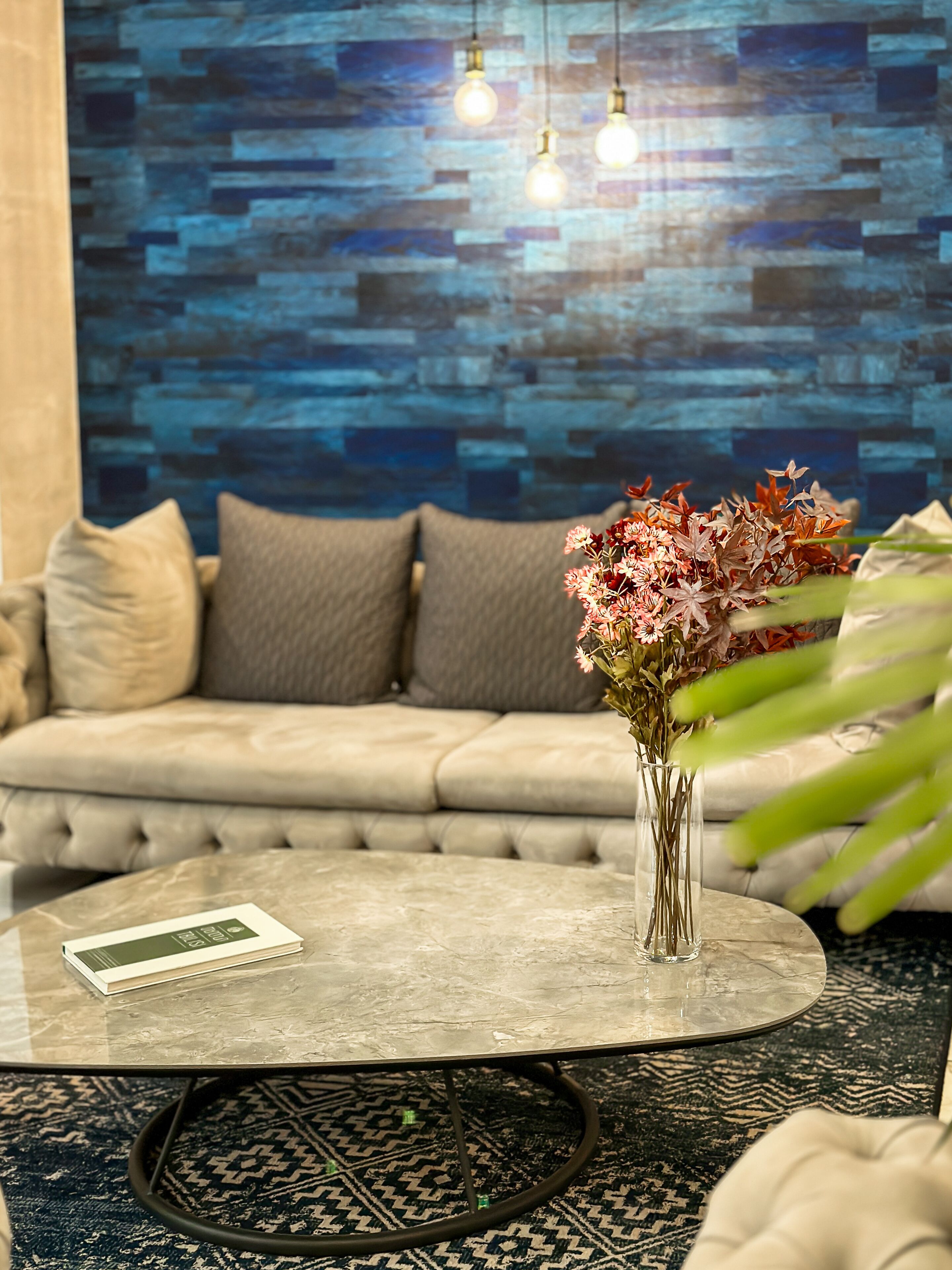 A modern living room with a sofa, a glass coffee table, and a vase with flowers.