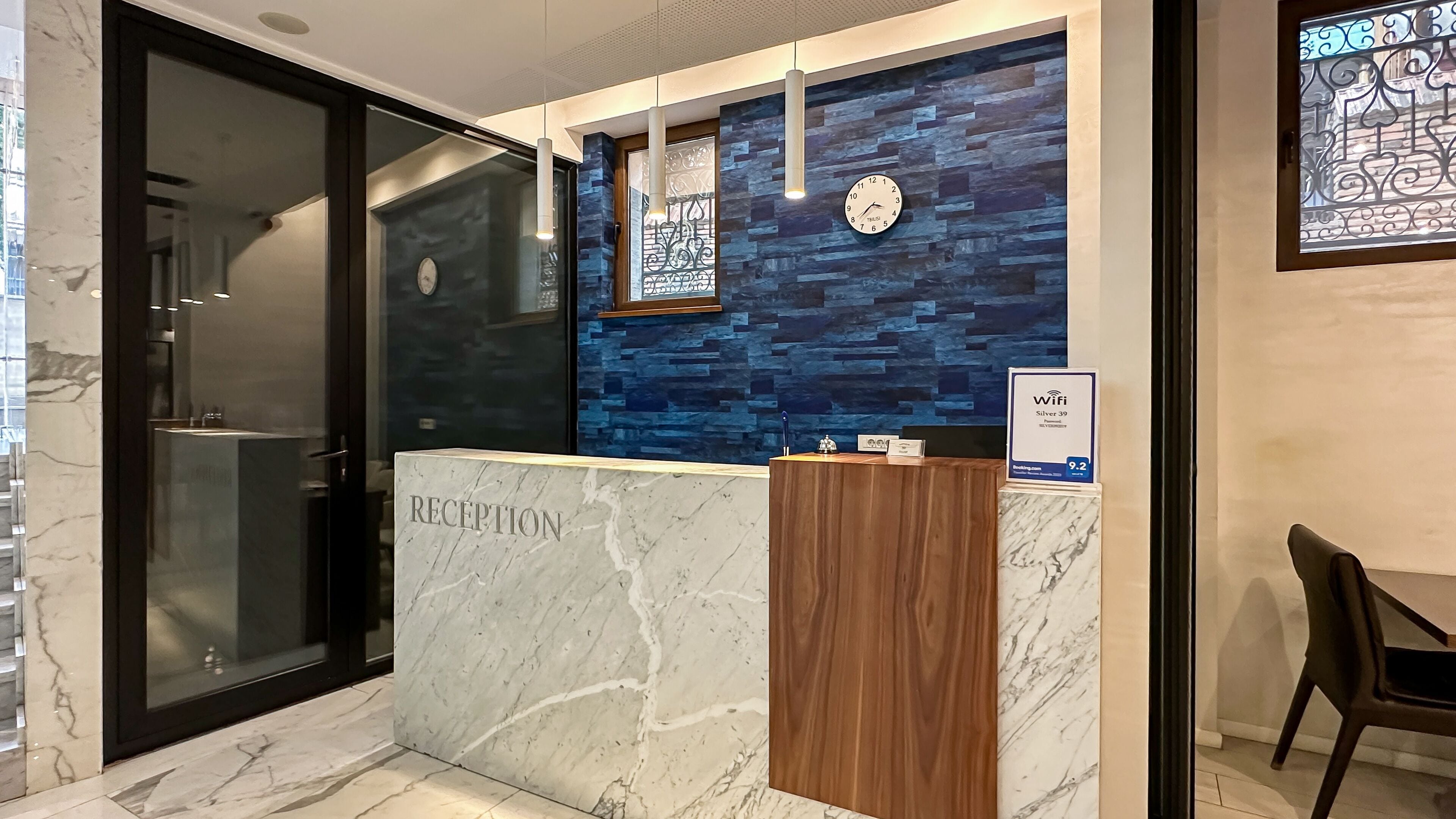 A reception desk with a marble top, a clock, and a sign indicating WiFi availability.