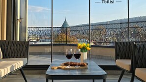 Een balkon met een tafel gedekt voor twee personen, met wijnglazen en een vaas met gele bloemen.