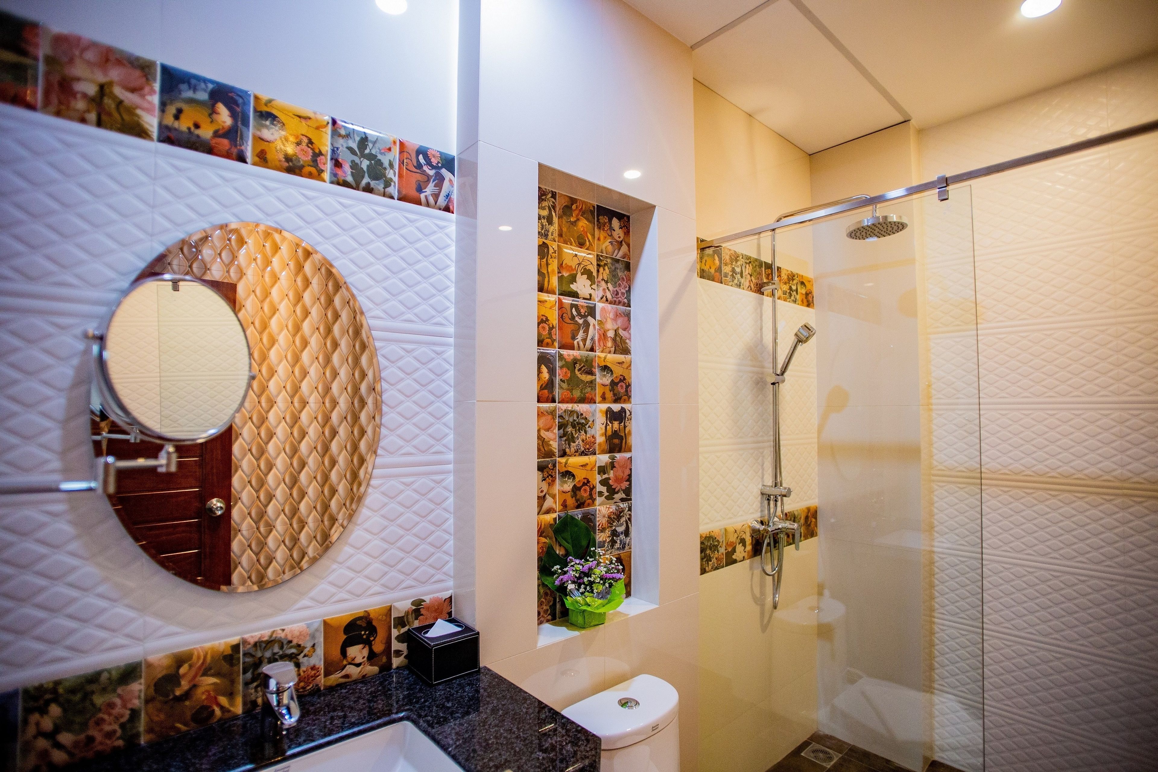 Un baño con un espejo redondo, un inodoro, una ducha y un lavamanos.