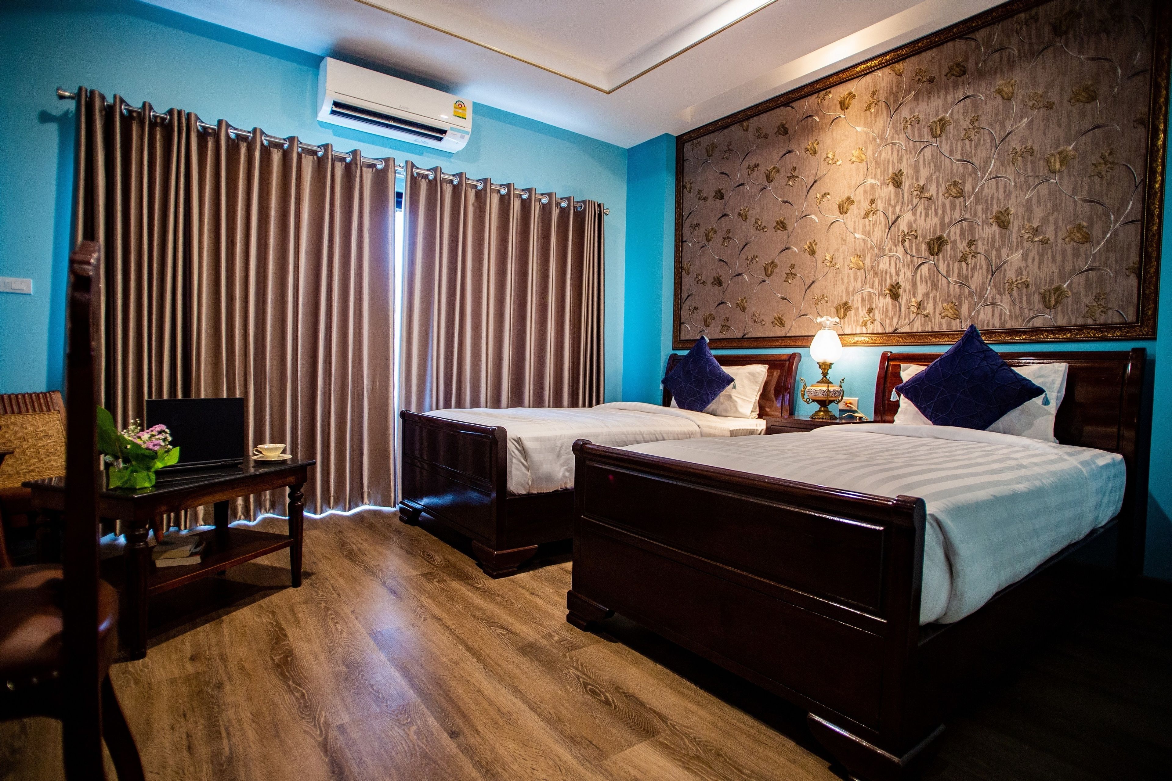 A hotel room with two beds, a desk with a computer, a TV, and a decorative wall panel.