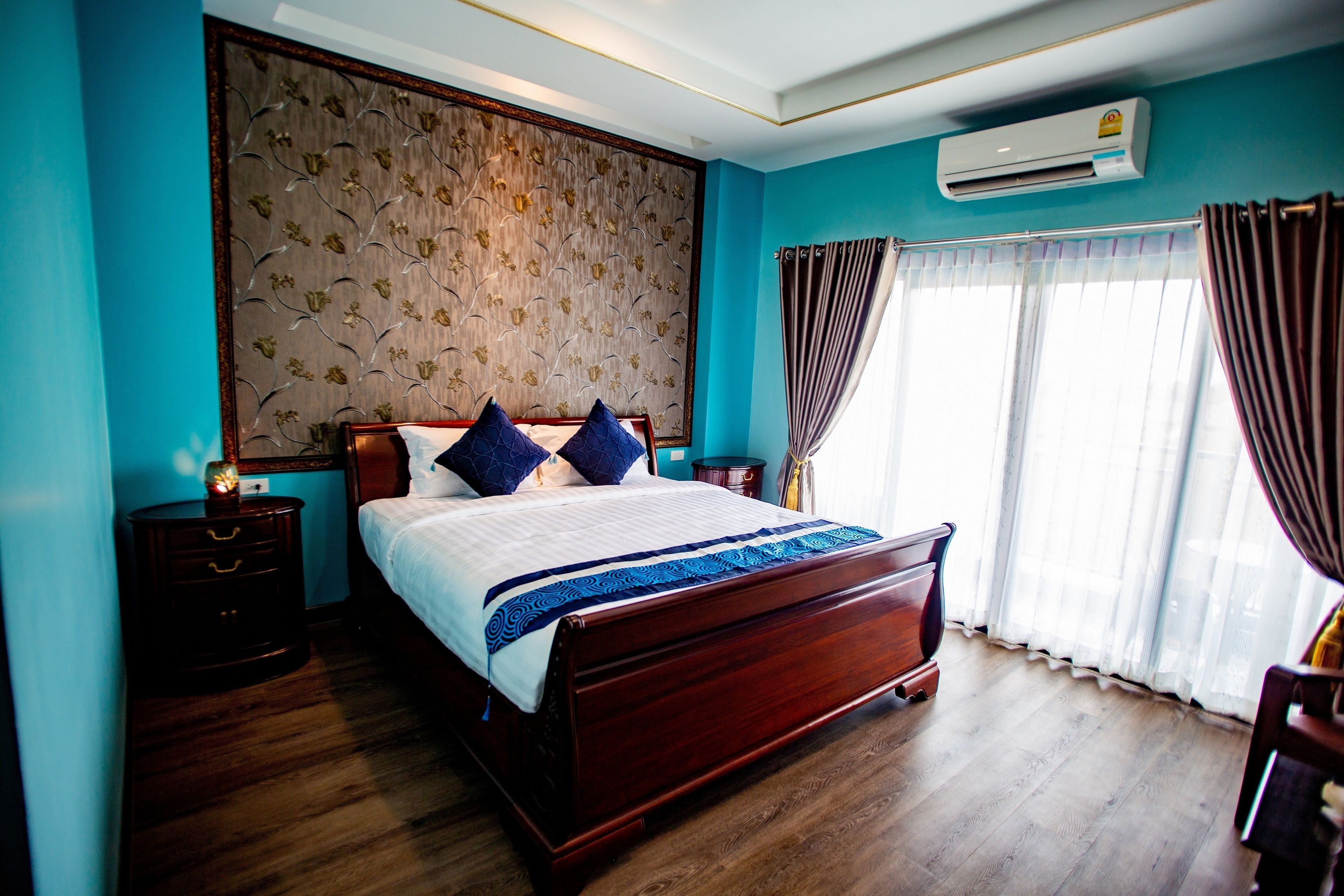 A bedroom with a wooden bed, a nightstand, a wall-mounted air conditioner, and a window with curtains.