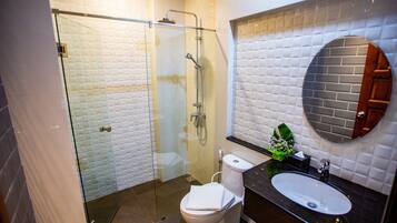 A modern bathroom with a glass shower enclosure, a white toilet, and a black sink with a mirror above it.