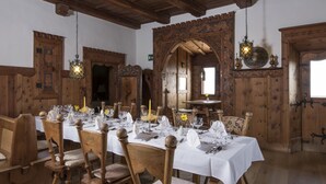 Un comedor con mesas y sillas de madera, manteles blancos y faroles colgantes.