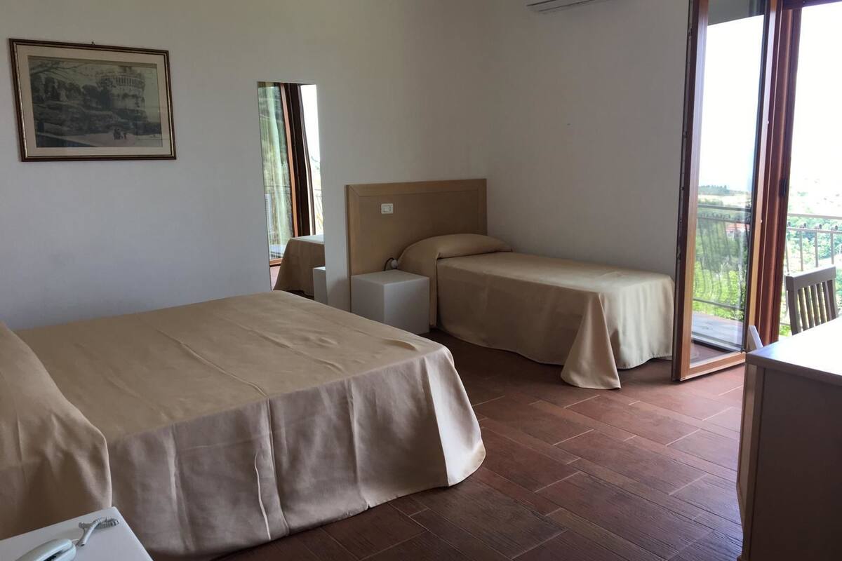 A hotel room with two beds, a small table, and a painting on the wall.
