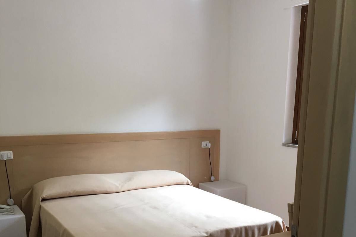 A simple, clean room with a bed, bedside tables, and a ceiling light.