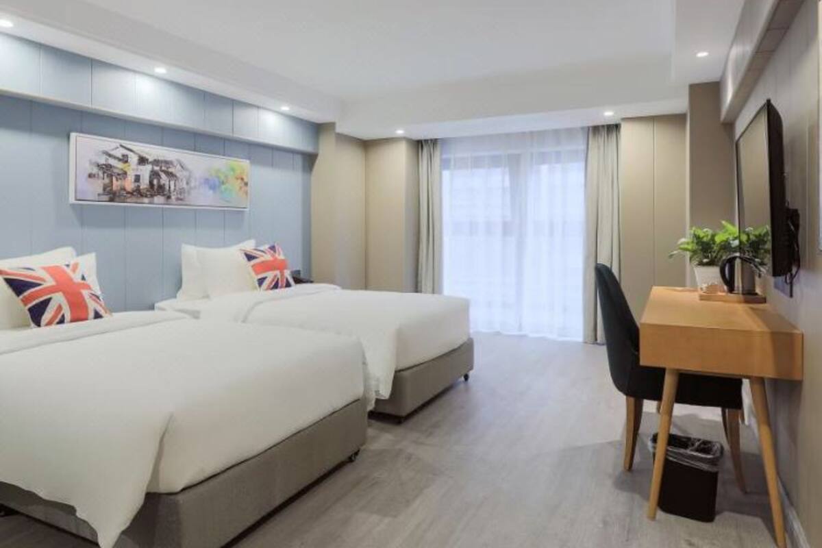 Ein Hotelzimmer mit zwei Betten, einem Schreibtisch und einem Stuhl.