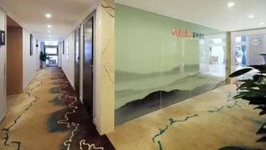 A hotel corridor with a patterned carpet, a green wall with a window, and a door leading to another room. - Vyluk Hotel Chongqing Airport (Chongqing)