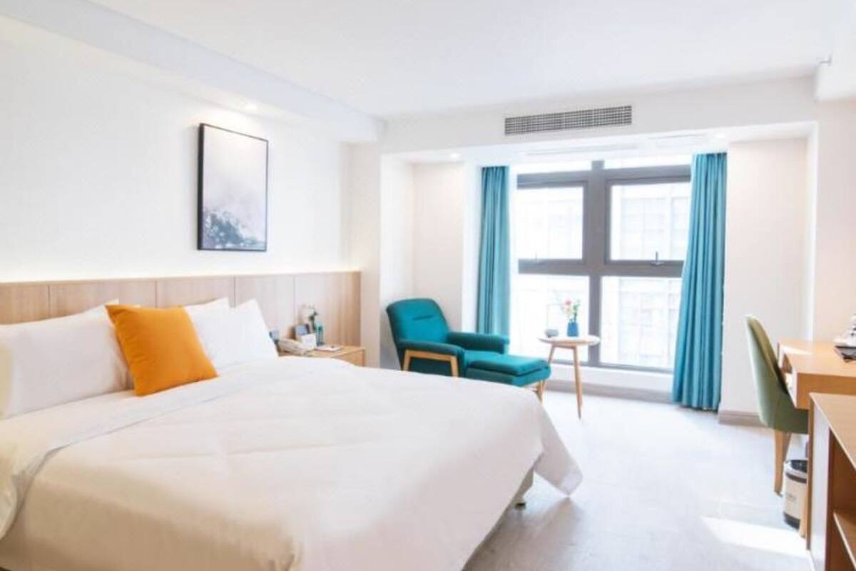 Ein Hotelzimmer mit einem großen Bett, einem Schreibtisch, einem Stuhl und einem Vorhangfenster.