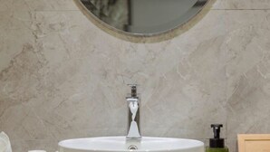 A bathroom with a round white sink, a mirror, and toiletries on the counter. - Vyluk Hotel Chongqing Airport (Chongqing)